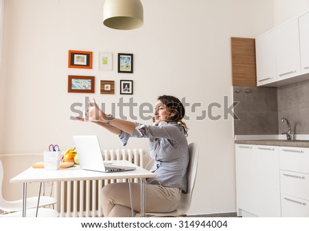 Attractive young woman working on her blog.She stretching after hard work.