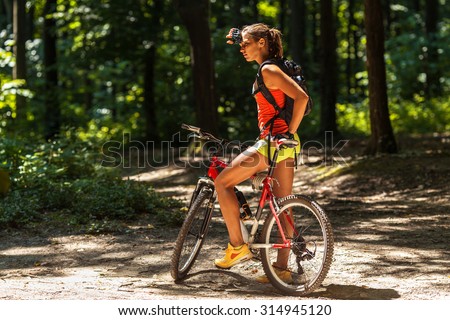 Woman riding a mountain bike in the forest.Taking a break and looking around.