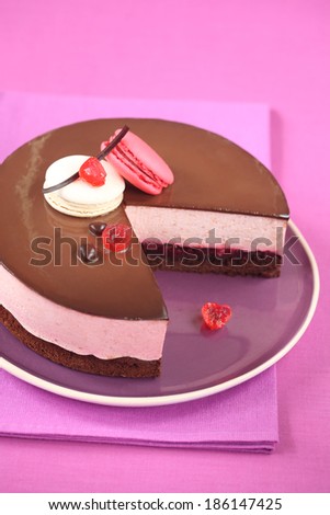 Chocolate Cherry Mousse Cake decorated with macarons, on a purple plate and on a purple tablecloth.