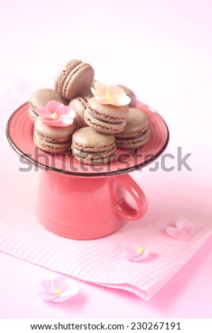 Chocolate Macarons on a bright pink plate and tea cup, on a pink napkin and pink background.