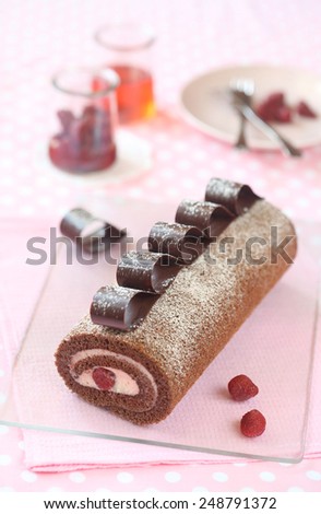 Chocolate Strawberry Swiss Roll Cake decorated with chocolate loops on a pink napkin and light pink background.