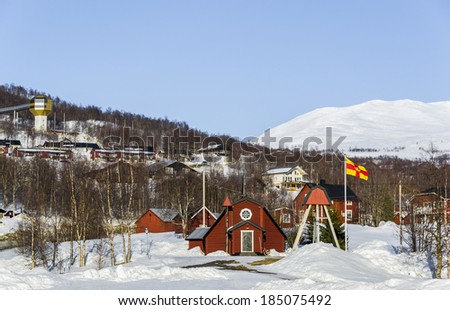 Small church at Hemavan ski resort in Sweden. Small red wooden church in Swedish village and ski resort Hemavan in winter with mountains in the background.