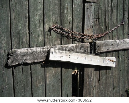 An old broken, weathered barn door with a chain.