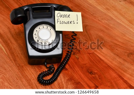 Retro black telephone with reminder note to order flowers