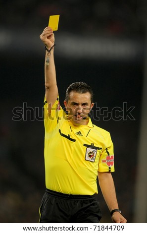 BARCELONA - FEB 20: Referee Ramirez Dominguez delivers yellow card during the match between FC Barcelona and Athletic de Bilbao at the Nou Camp Stadium on February 20, 2011 in Barcelona, Spain