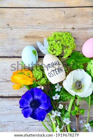 Easter egg with text in German and spring flowers on a rustic wooden background - Frohe ostern means happy Easter Foto d'archivio © 