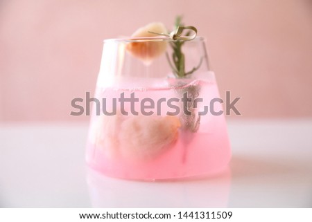 Cóctel rosa con romero y lichi de fondo rosa
