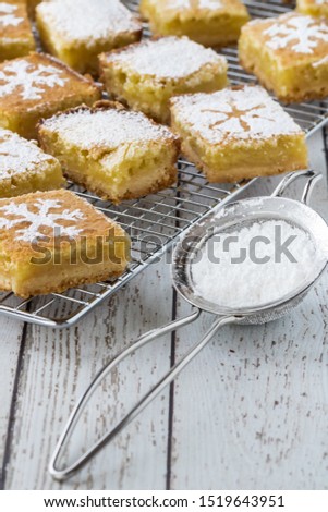 Close up top down view of lemon squares with snowflake designs on a cooling rack.