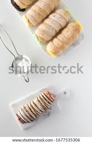 Top down view of cannoli against a white background with a powdered sugar sifter.