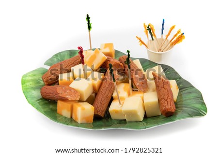 orange and white cheddar cheese cubes and pepperoni sausage chunks on a stylish leaf shaped plate and fancy toothpicks on white