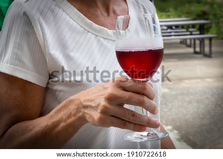 Une dame tient un verre réfrigéré de vin rouge.