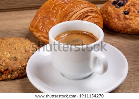 a white cup of espresso coffee with a selection of Danish pastry