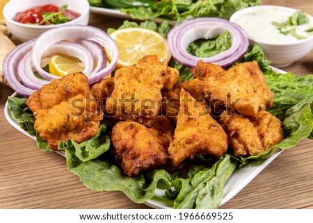 a plate of traditional Indian or Pakistani Fish Pakora, basa fish dipped in chick pea batter and deep fried