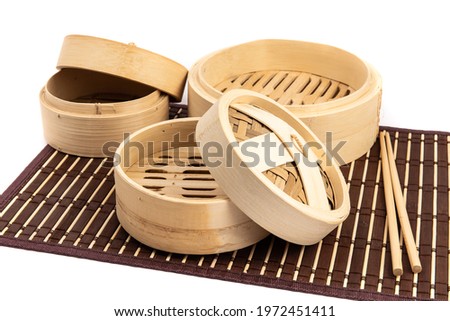 Asian or Chinese bamboo vegetable and dumpling steamers isolated on a bamboo table mat on white