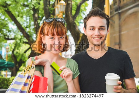 Happy young couple with shopping bags after shopping walking on the streets. Consumerism concept. 