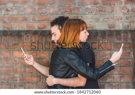 Portrait of young couple hugging while each using their own smartphone. Problems in relationship. Stock foto © 