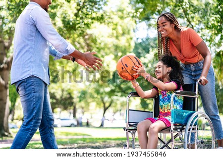 Girl in a wheelchair playing basketball with her family.