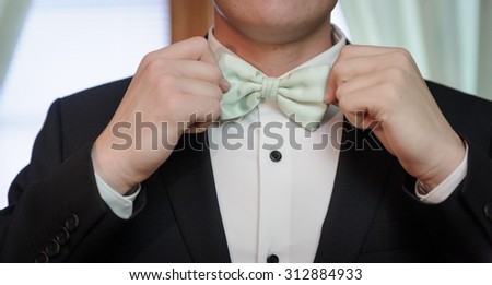 Groom fixing bow tie