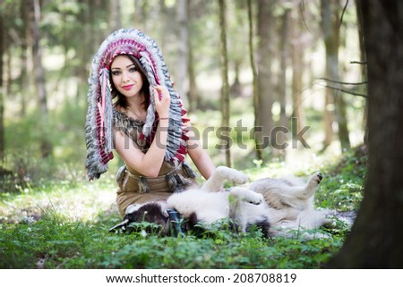 Indian girl in war bonnet playing with husky dog