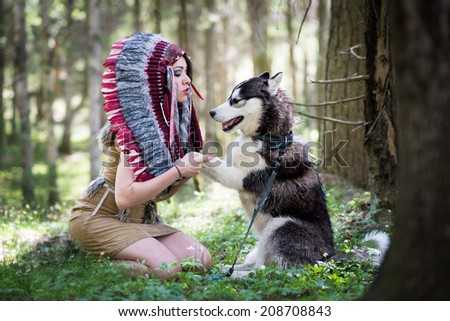Indian girl in war bonnet playing with husky dog