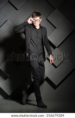 Handsome elegant man in black suit with glasses. Success on abstract dark background.