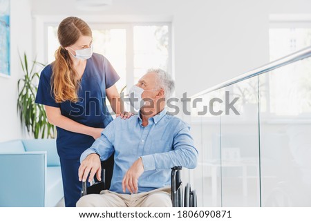Young woman nurse explaining information to man patient in wheelchair in medical face mask while talking together in hospital. Epidemic and virus concept