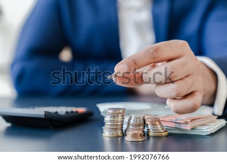 Businessman holding euro cents coins dollar bills on table with pile of coins and banks calculator, managing dividing money to save and invest it to make income. Saving money and investing concept. Stockfoto © 