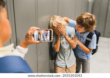 Schoolchildren cruel boys filming on the phone torturing bullying their classmate in school hall. Puberty difficult age Foto stock © 