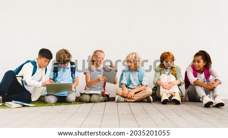 Multi-ethnic mixed-race schoolchildren kids classmates students pupils sitting together at school yard holding books copybooks talking before classes lessons. Back to school after summer holidays Foto stock © 