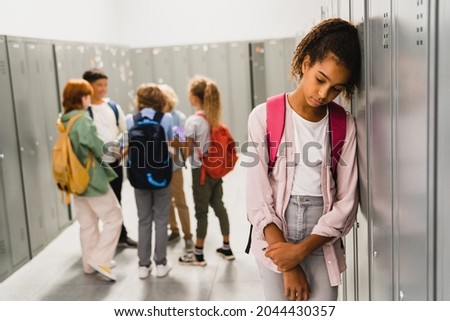 Lonely sad african-american schoolgirl crying while all her classmates ignoring her. Social exclusion problem. Bullying at school concept. Racism problem Foto stock © 