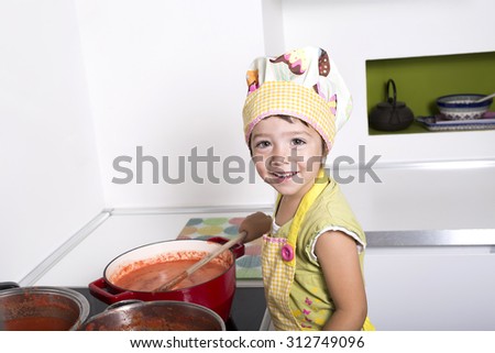 Little girl cooking tomato sauce. Preparing stores for the winter.