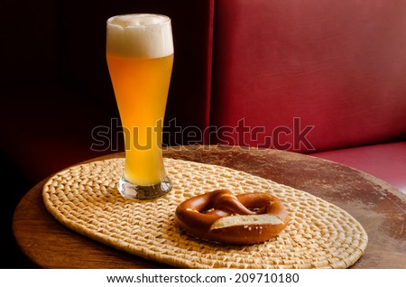 large beer glass and a pretzel on a woven serving tray in a pub