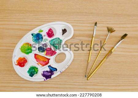 palette with smudges of paint and brushes on a wooden table