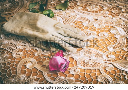 female glove holding a rose on an elegant table cloth in vintage look