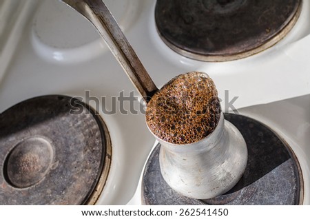Turkish coffee pot with boiling coffee on an old electric stove.