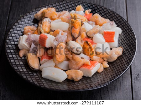 Mixed frozen seafood on black plate and black background