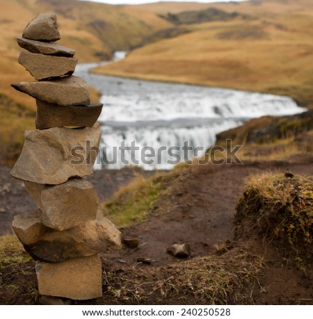 single cairn on focus and waterfall background out of focus
