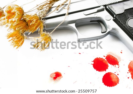 A Hand Gun set on an isolated white background with stems of dried flowers draped over the gun barrel.