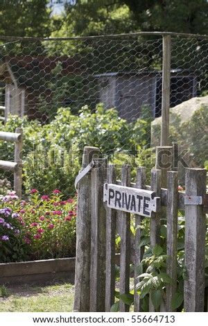 A wooden garden gate with a hand painted sign with the word private nailed to its front. The gate is the entrance to a vegetable garden and allotment located in rural Devonshire countryside, England.