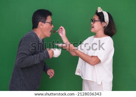 A wife asked her husband, who was holding a cup of coffee, to try a piece of cake that she ate. Stock fotó © 