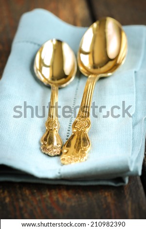 Vintage golden spoons placed on blue linen napkin over wooden table