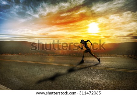 Silhouette of a fit woman running at sunset in the mountains. Training, jogging, healthy lifestyle.