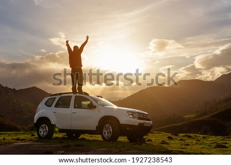 person with arms raised and on the roof of his off-road car watching the sunset on the mountain after a day of travel and adventure. Active turism. mountain activities. Photo stock © 