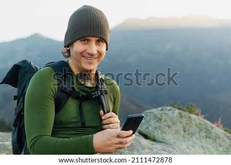 middle aged white man with tattoos and backpack holding mobile phone and looking at camera. Hiker doing a section of the Camino de Santiago in Asturias, Spain. Pilgrim