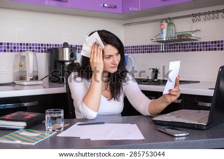 stressed young woman is doing banking and administrative work holding bills at home