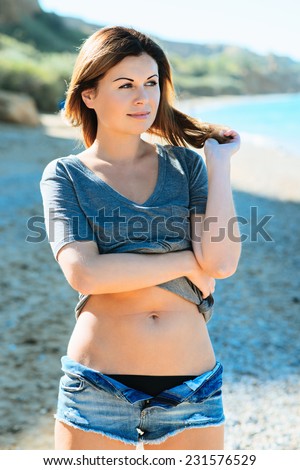 young pretty girl in sexy shorts posing at beach. Fashion summer outdoor portrait of beautiful young woman