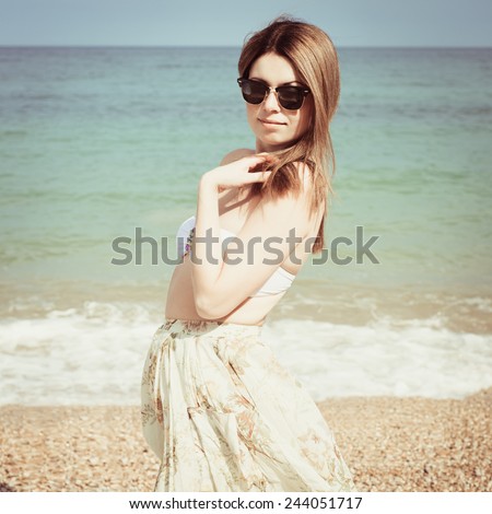 Outdoor fashion warm colors portrait of young sensual happy woman in skirt, bikini and sunglasses. model posing. Photo with instagram style filters