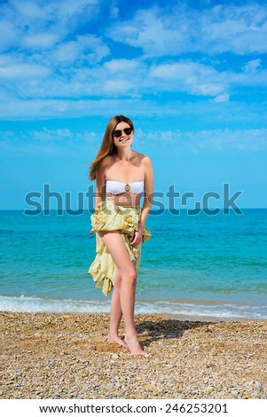 Outdoor fashion warm colors portrait of young sensual happy woman in skirt, bikini and sunglasses. model posing