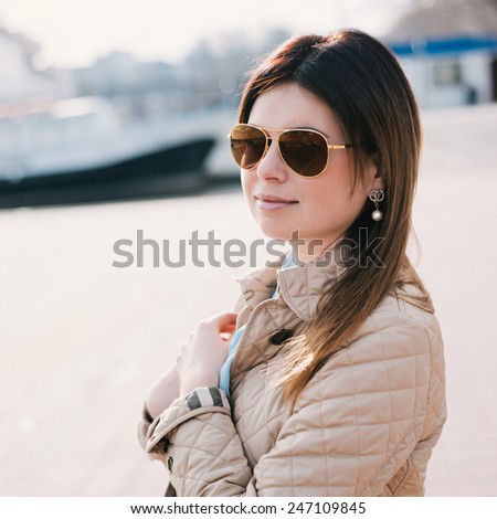 Outdoor lifestyle portrait of woman walking at coast. Fashion style. young woman dressed in branded clothes enjoys warm, spring weather. Photo with instagram style filters