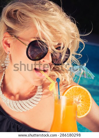 beautiful, suntanned, young sexy woman drinking cocktail, and enjoys in the summer afternoon near the pool